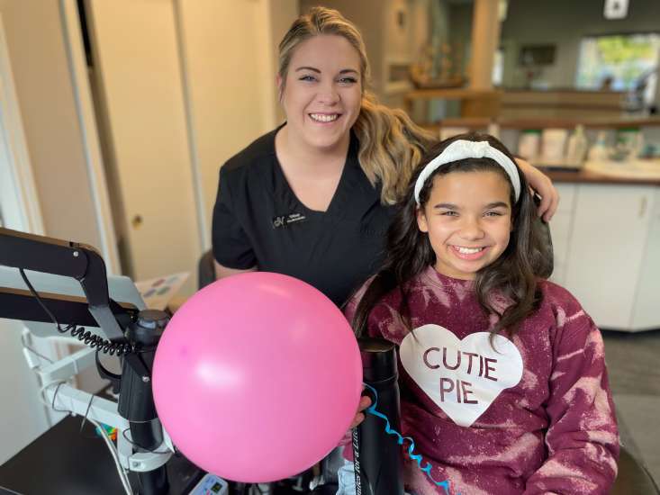 Team member and patient with a pink balloon