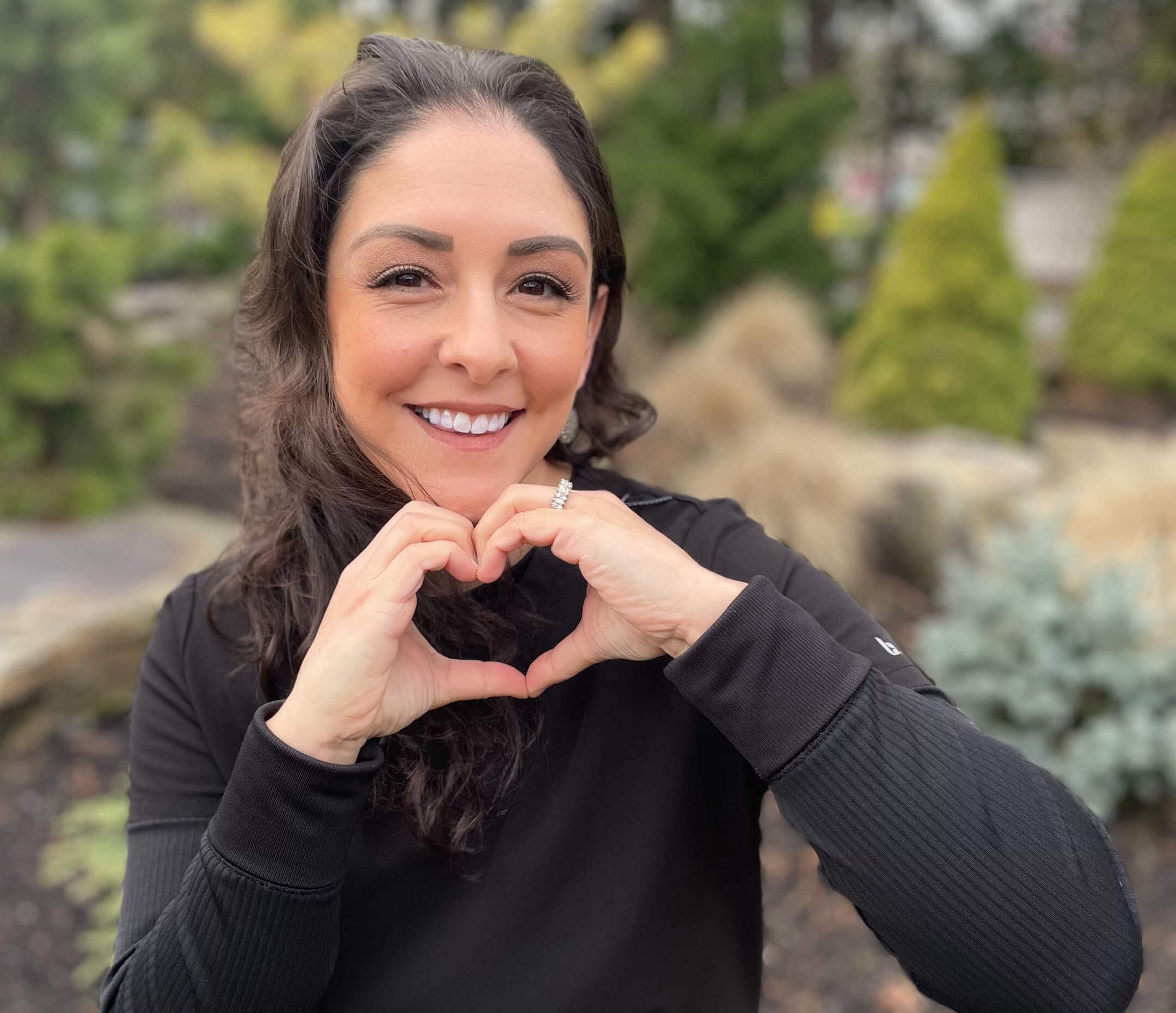 Team member posing with hands forming a heart